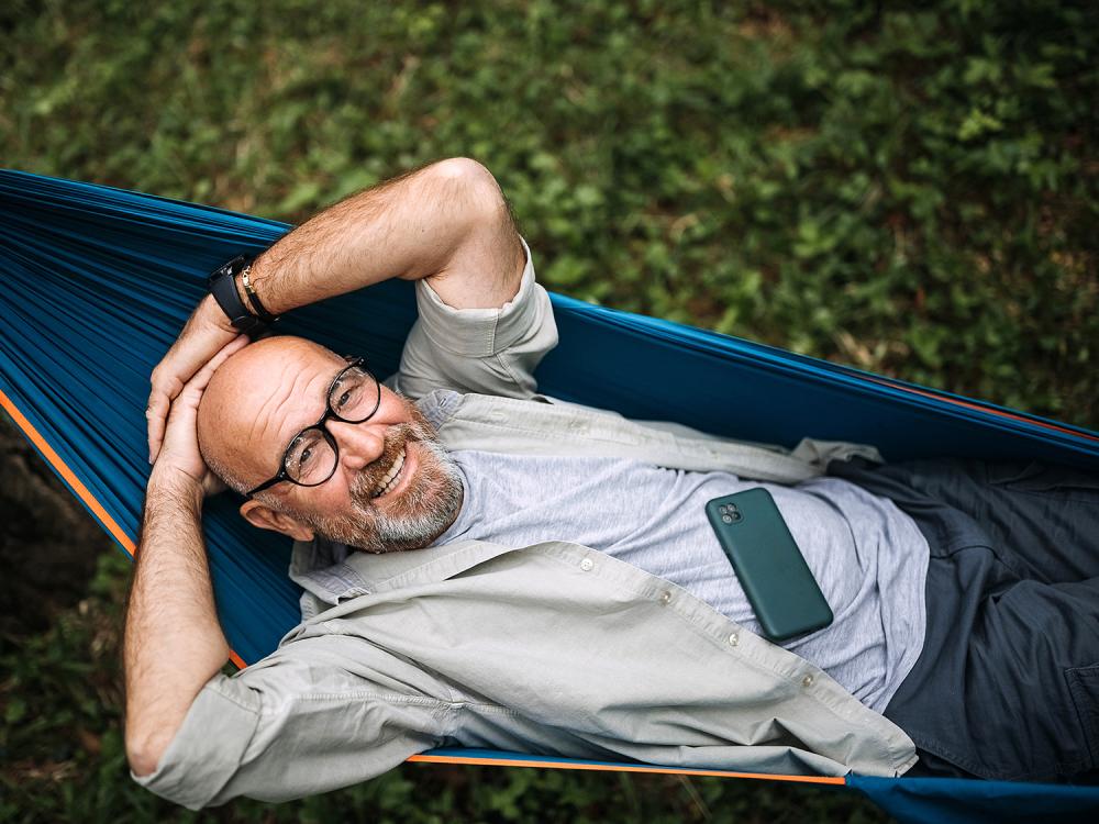 Older man lying in a hammock smiling