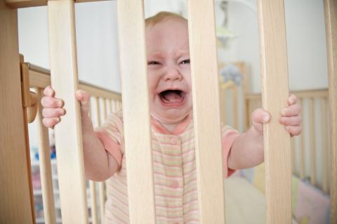 A crying baby in a crib.