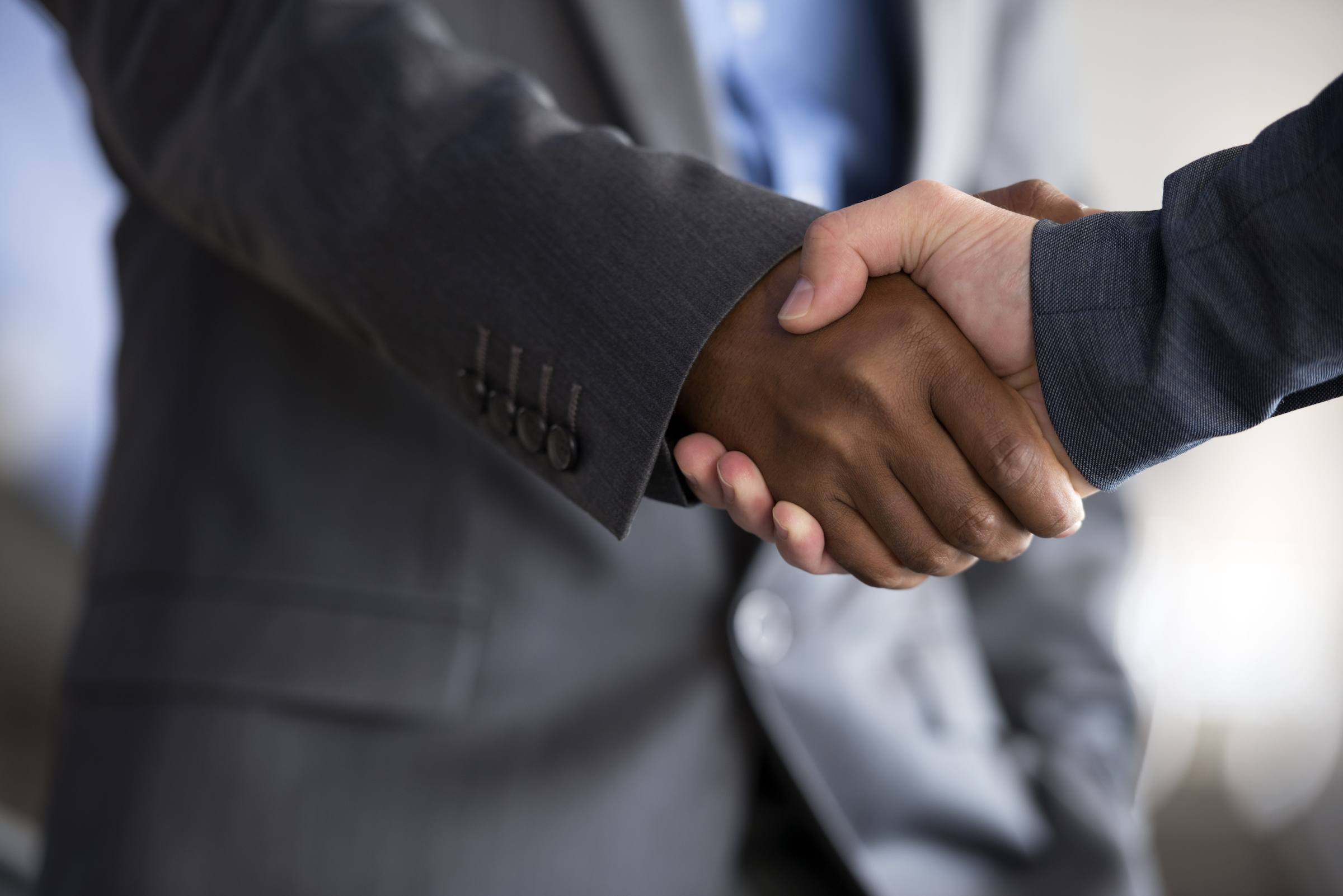 Two men shaking hands, one black, one white