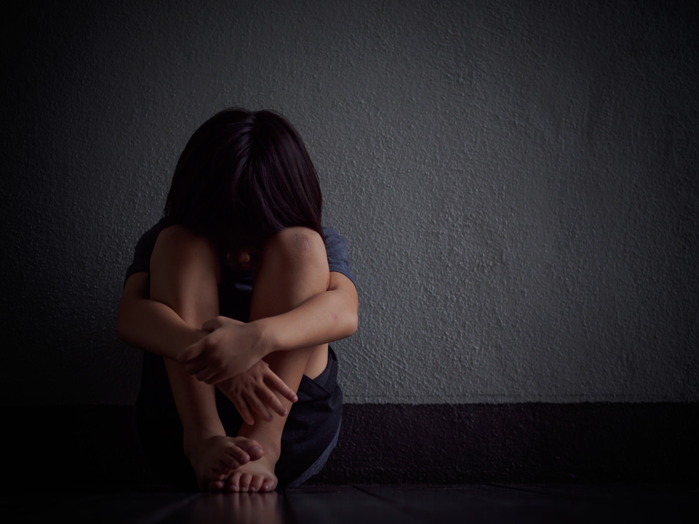 Little boy sad and alone sitting in the dark.