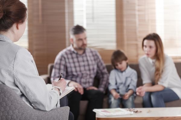 Family with young child talking to  a female therapist