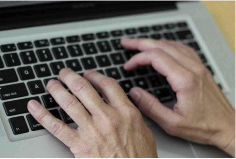 Hands using a laptop keyboard