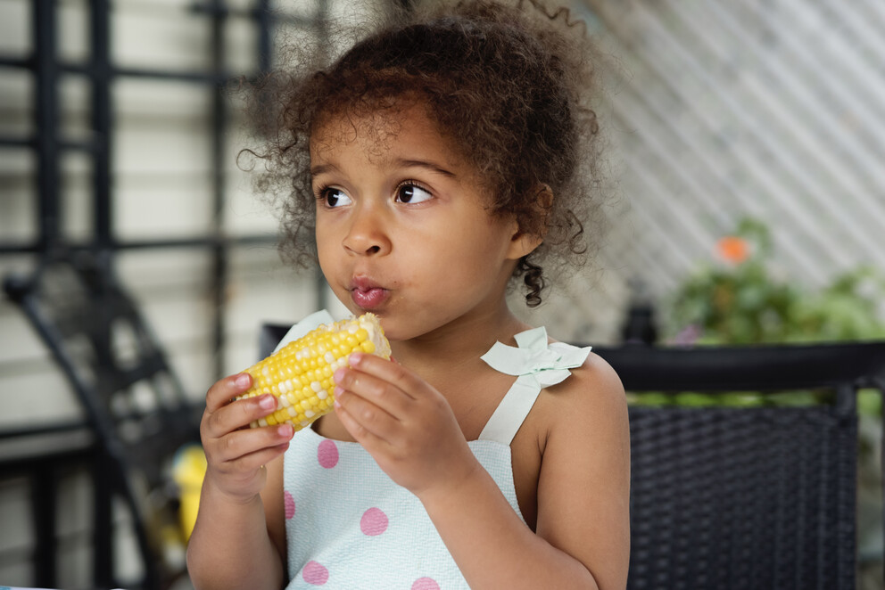 Small child eating corn on the cob
