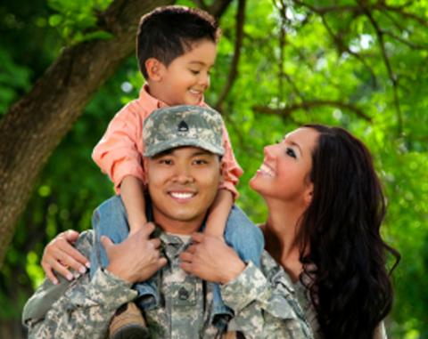 A military dad with his son on his shoulders and his wife standing next to them.