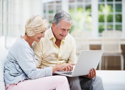 Two older adults looking at a laptop screen together.
