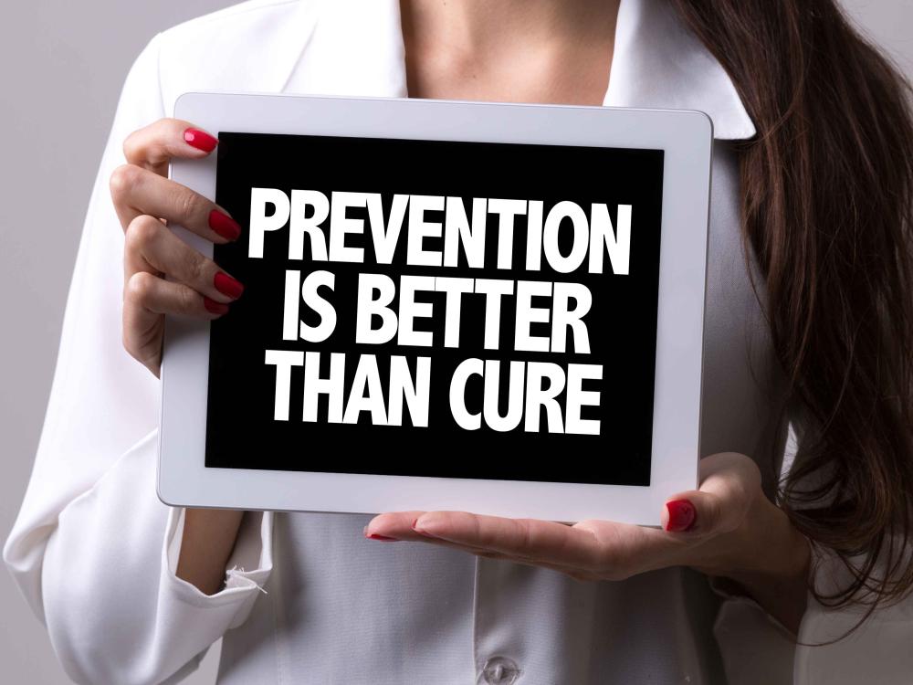 Woman holding prevention is better than cure sign.