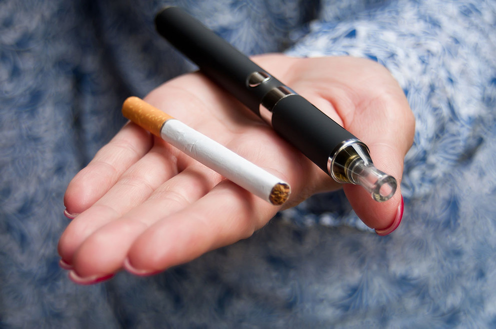 Open palm with a cigarette and e-cigarette