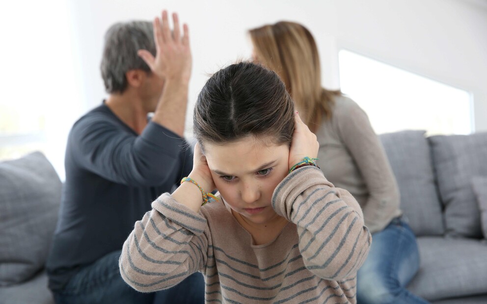 Parents fighing with teen girl covering her ears.