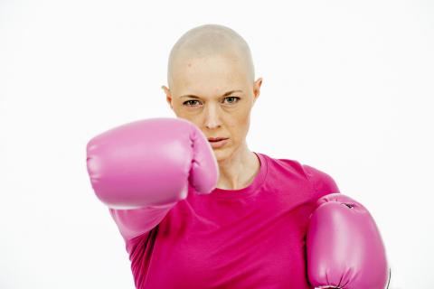 Woman fighting cancer in pink shirt and boxing gloves