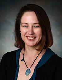 Lisa Gatzke-Kopp headshot in short brown hair and black shirt with blue necklace.