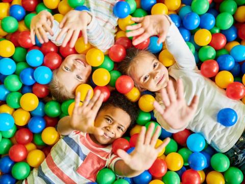 Four young children playing in ball pit.
