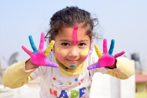Young girl with facepaint on hands and face smiling.
