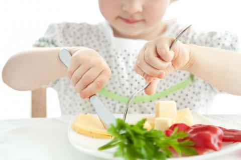 Young child eating a plate of fruit and vegetables