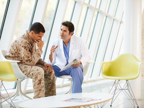 Doctor talking to a young, enlisted man.