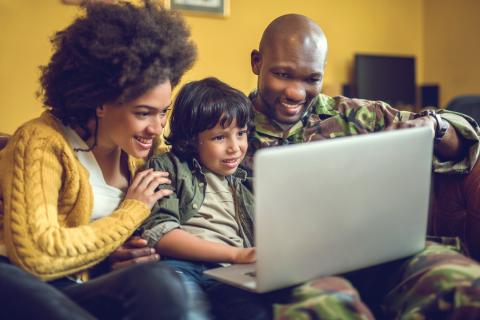 Military family looking at laptop smiling