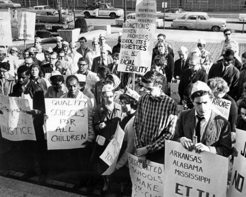 People with picket signs in favor of racial equality and school desegregation.