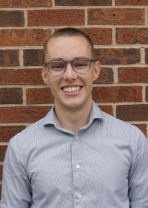 Headshot of Christopher Crawford with short dark brown hair in light blue shirt.