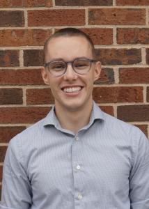 Headshot of Christopher Crawford with short dark brown hair in light blue shirt. 