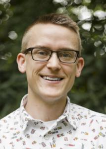 Headshot of David Lydon-Staley with blonde hair, glasses, and white shirt with colorful graphics.