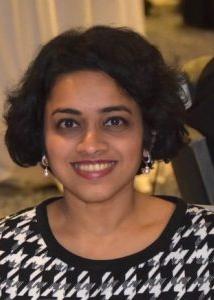 Headshot of Aparna Parikh with short dark hair and a houndstooth pattern sweater with earrings.
