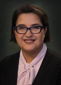 Headshot of Sara Imanpour, a woman with short dark hair, glasses, a black jacket, and pink shirt with a bow.