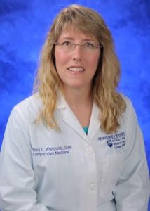 Headshot of Tiffany Whitcomb, a white woman with long blonde hair and glasses wearing a white lab coat.